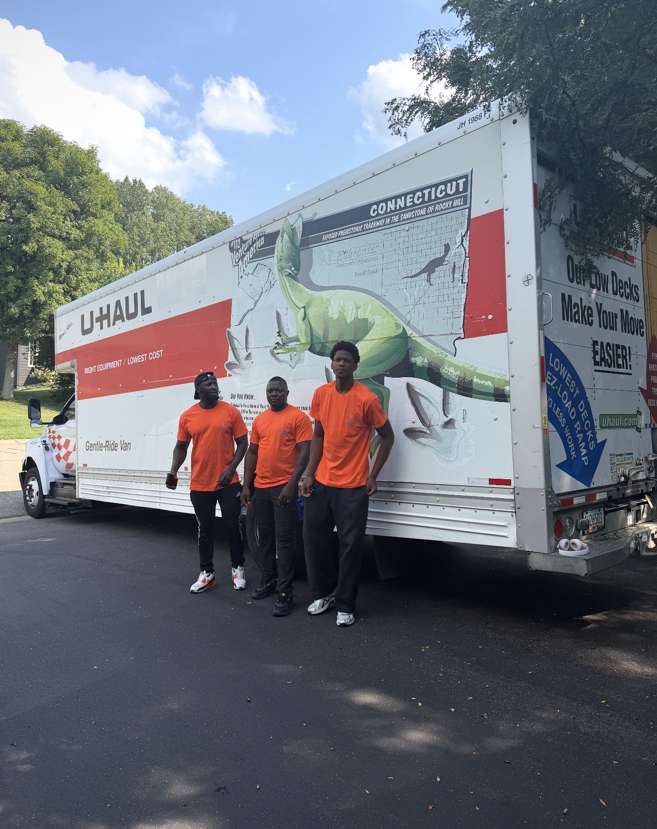 Burray Movers crew in orange shirts standing by a loaded moving truck